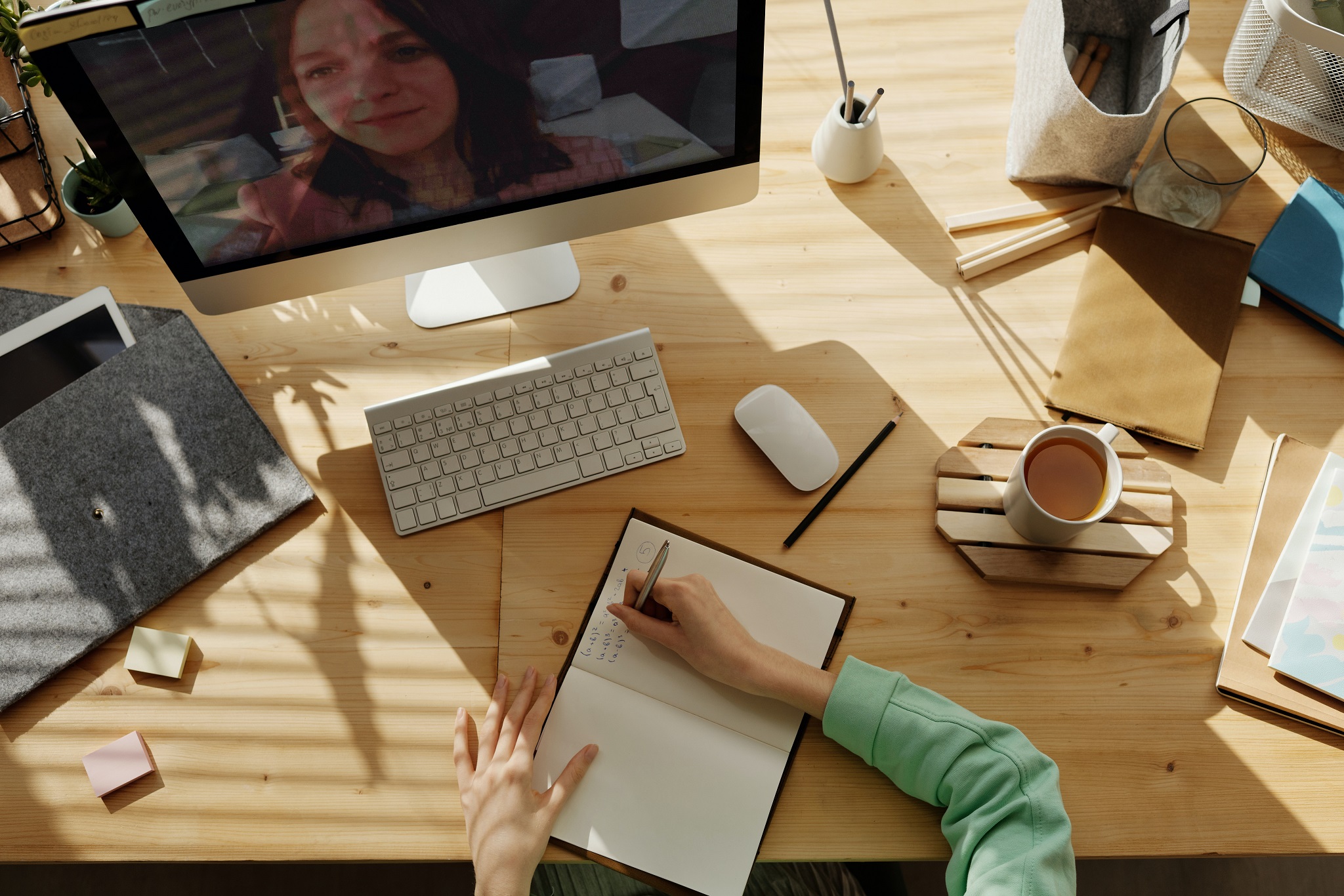 overhead photo of desk with coffee and computer and woman taking notes