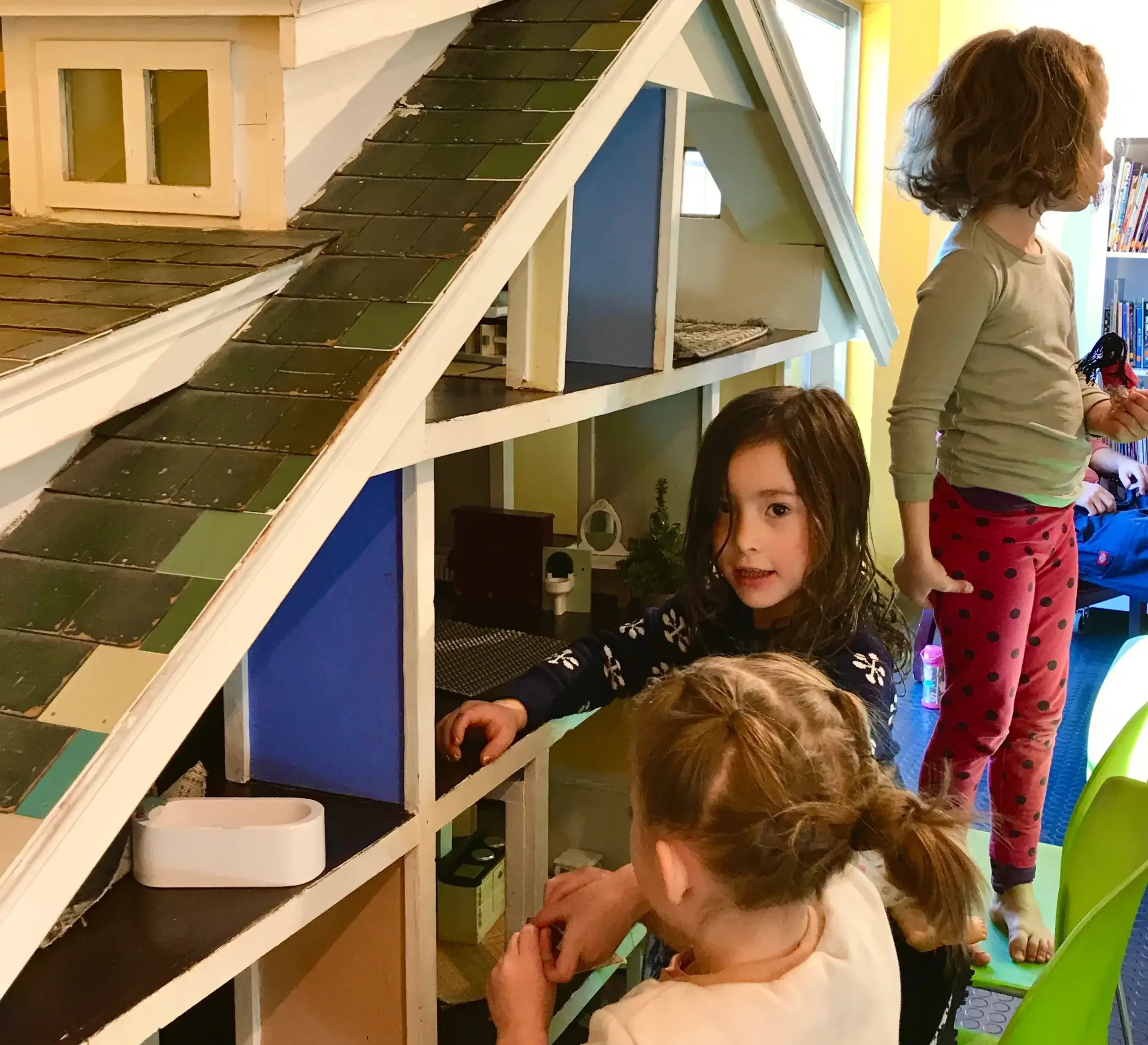 Three four year olds play with the giant dollhouse at the Santa Fe Children's Museum