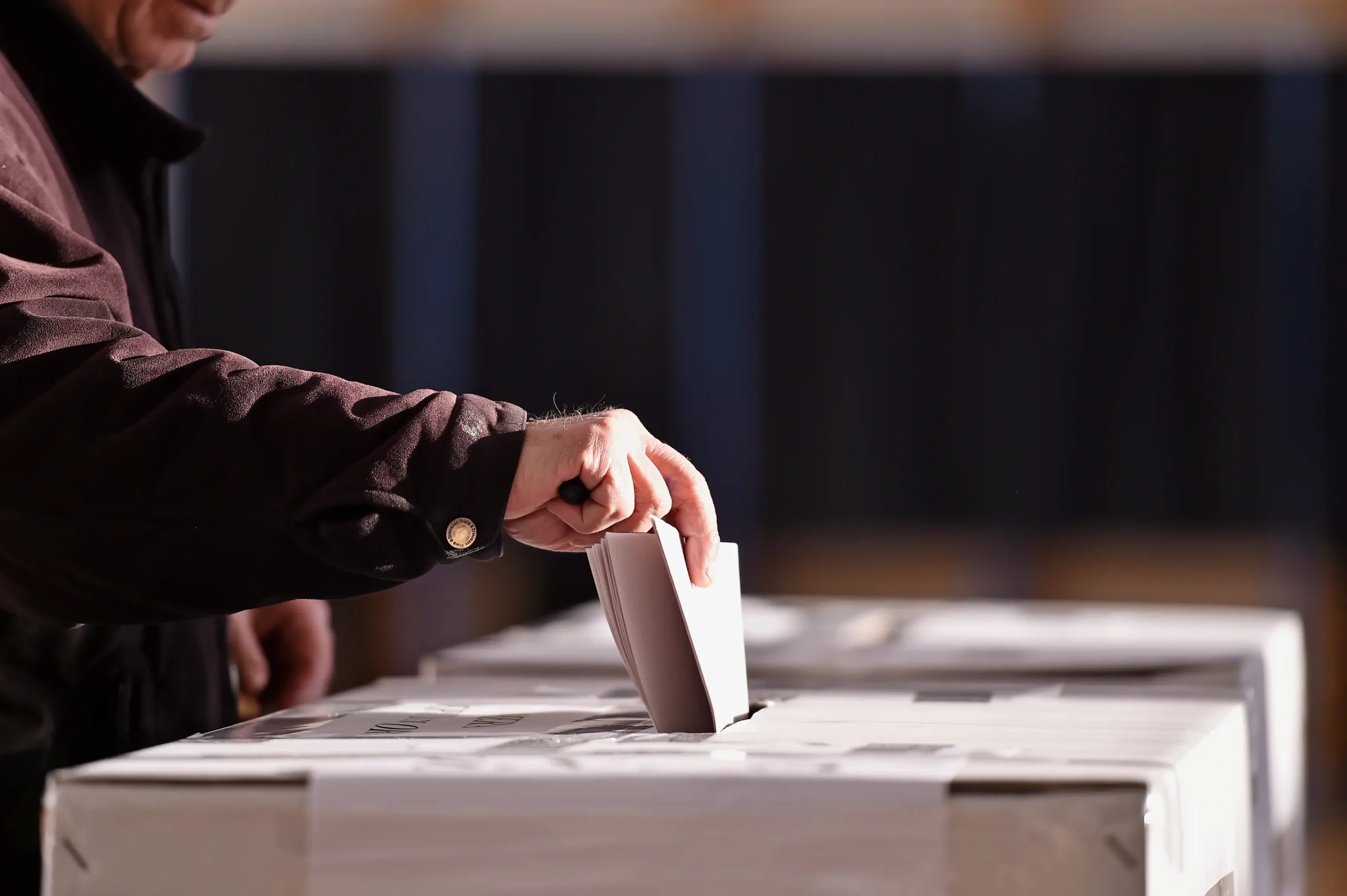 Election Cover Photo person inserting paper ballot at voting station